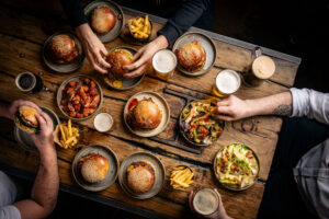 A group of people eating burgers and drinking craft beers